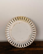 Decorative ceramic plate with scalloped edge on a wooden surface