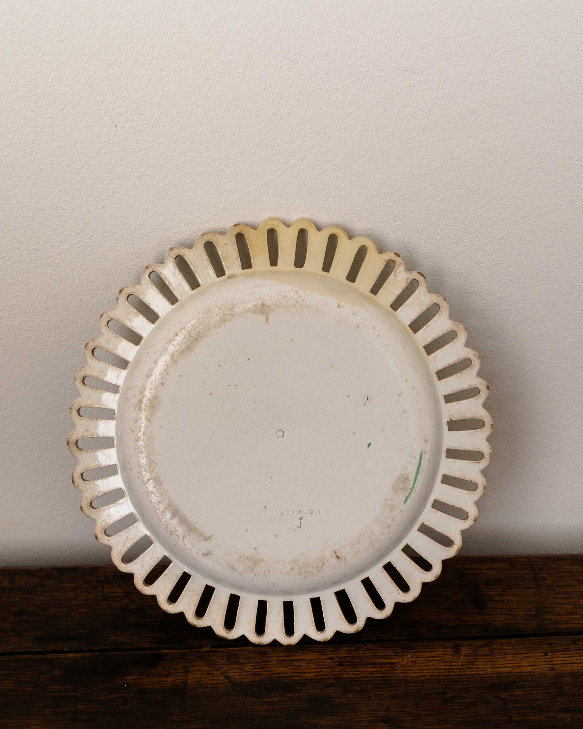Decorative ceramic plate with scalloped edge on a wooden surface