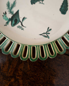 Decorative ceramic plate with green shell patterns on a wooden surface