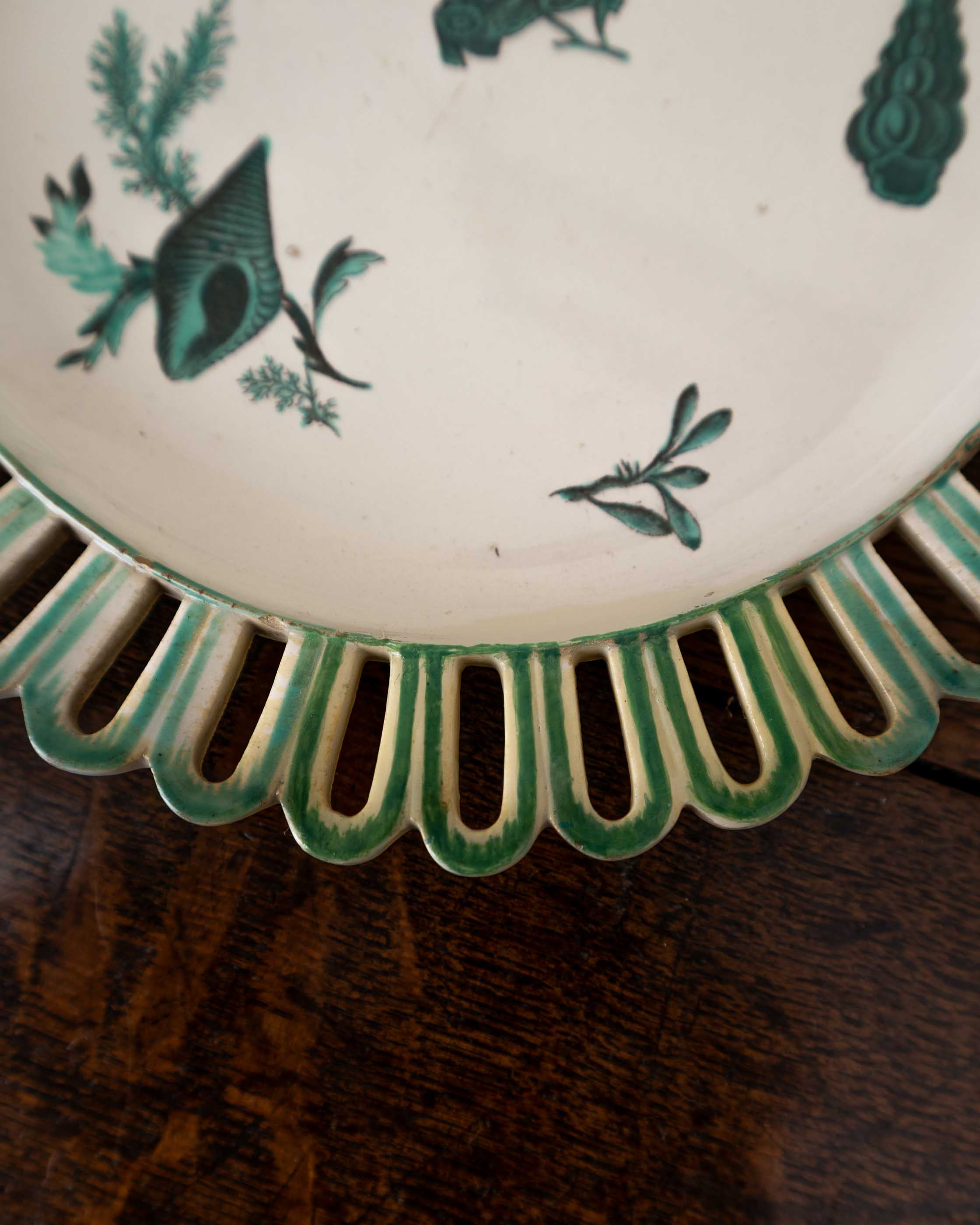 Decorative ceramic plate with green shell patterns on a wooden surface
