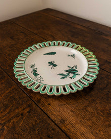 Decorative ceramic plate with green rim and black shell design on a wooden surface