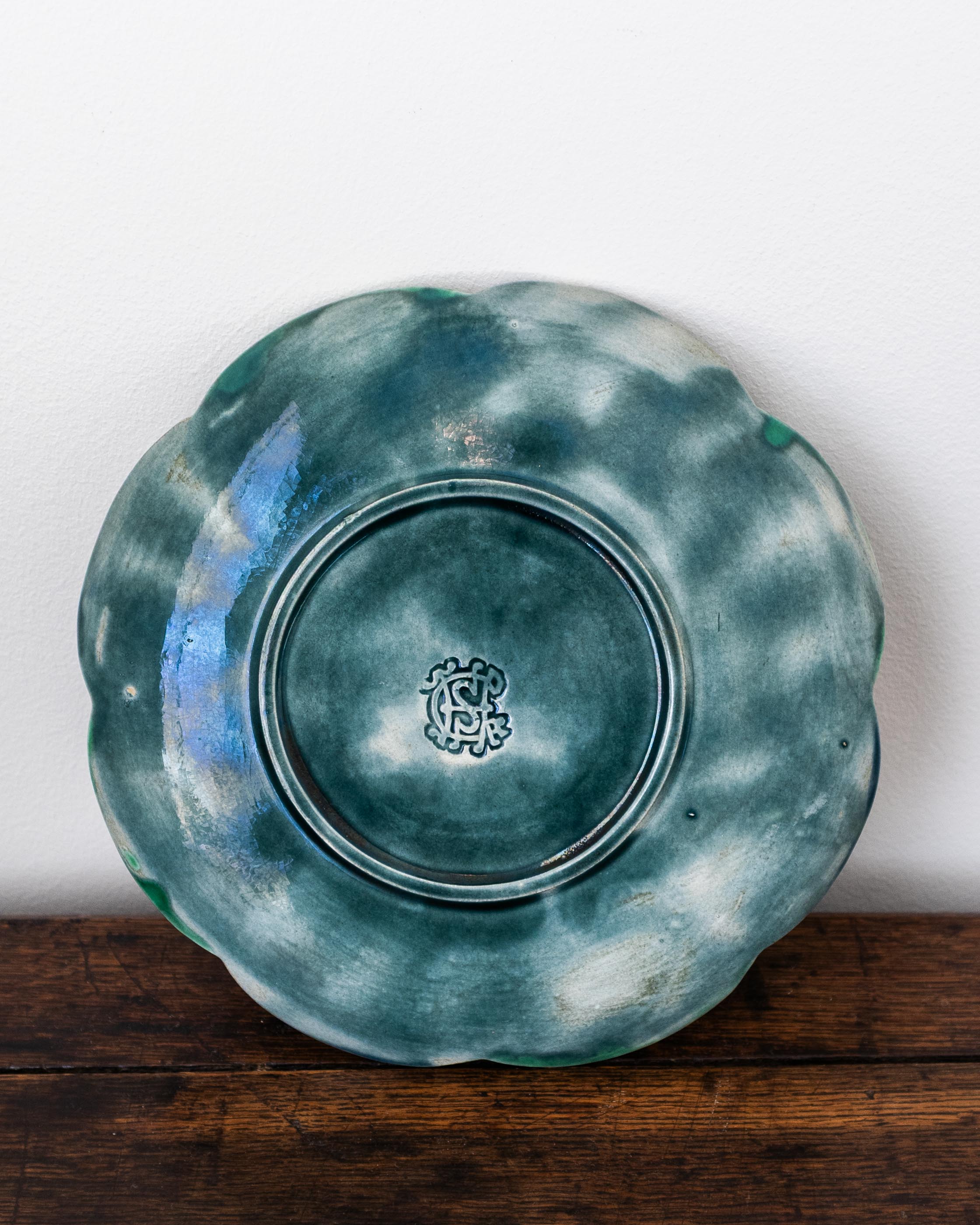 Green ceramic plate with a logo on a wooden surface and white background