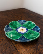 Ceramic plate with green leaf design and white center on a wooden surface