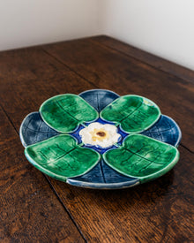 Ceramic plate with green leaf design and white center on a wooden surface