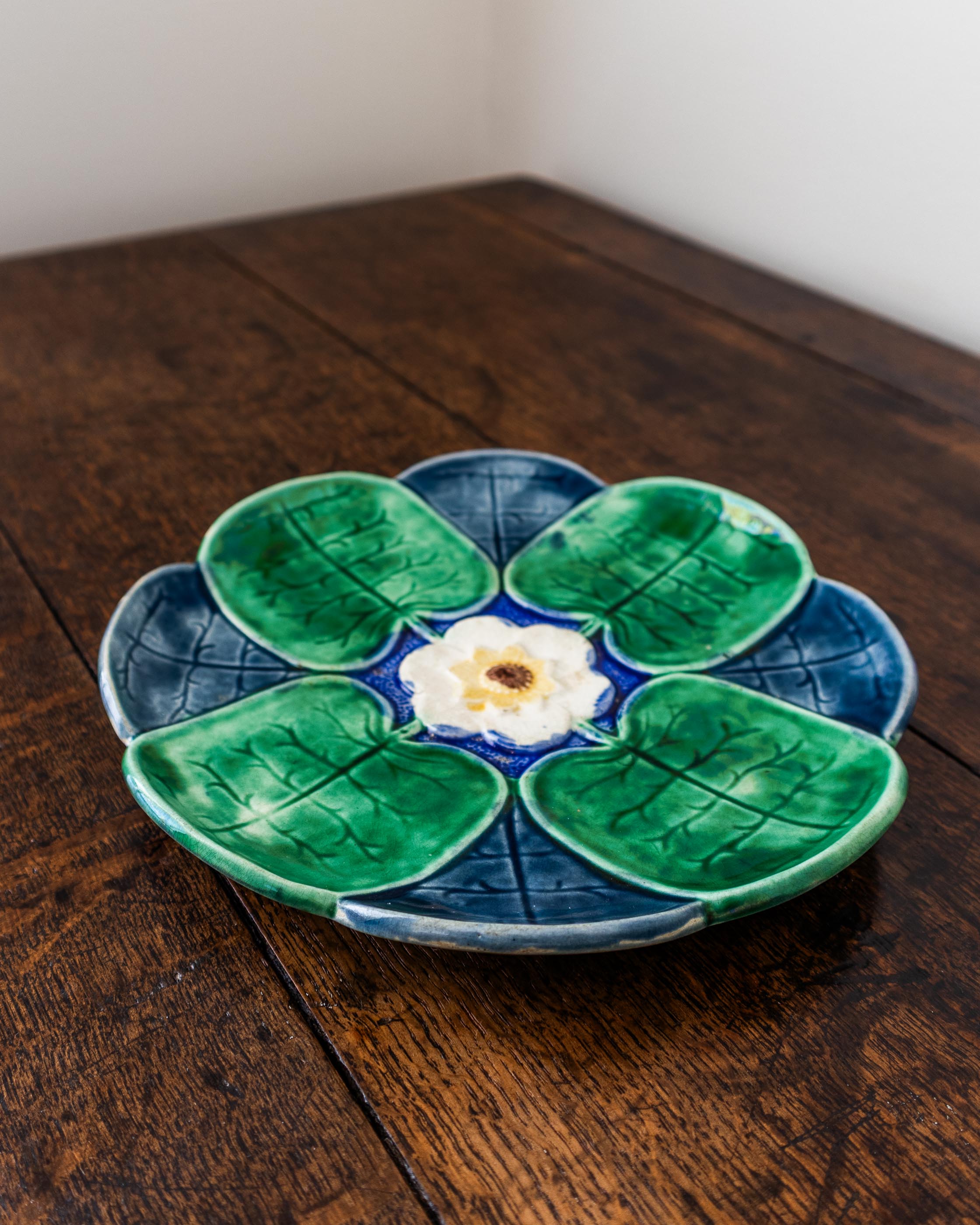 Ceramic plate with green leaf design and white center on a wooden surface