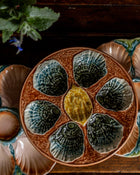 Ceramic oyster plate with shell designs on a wooden surface