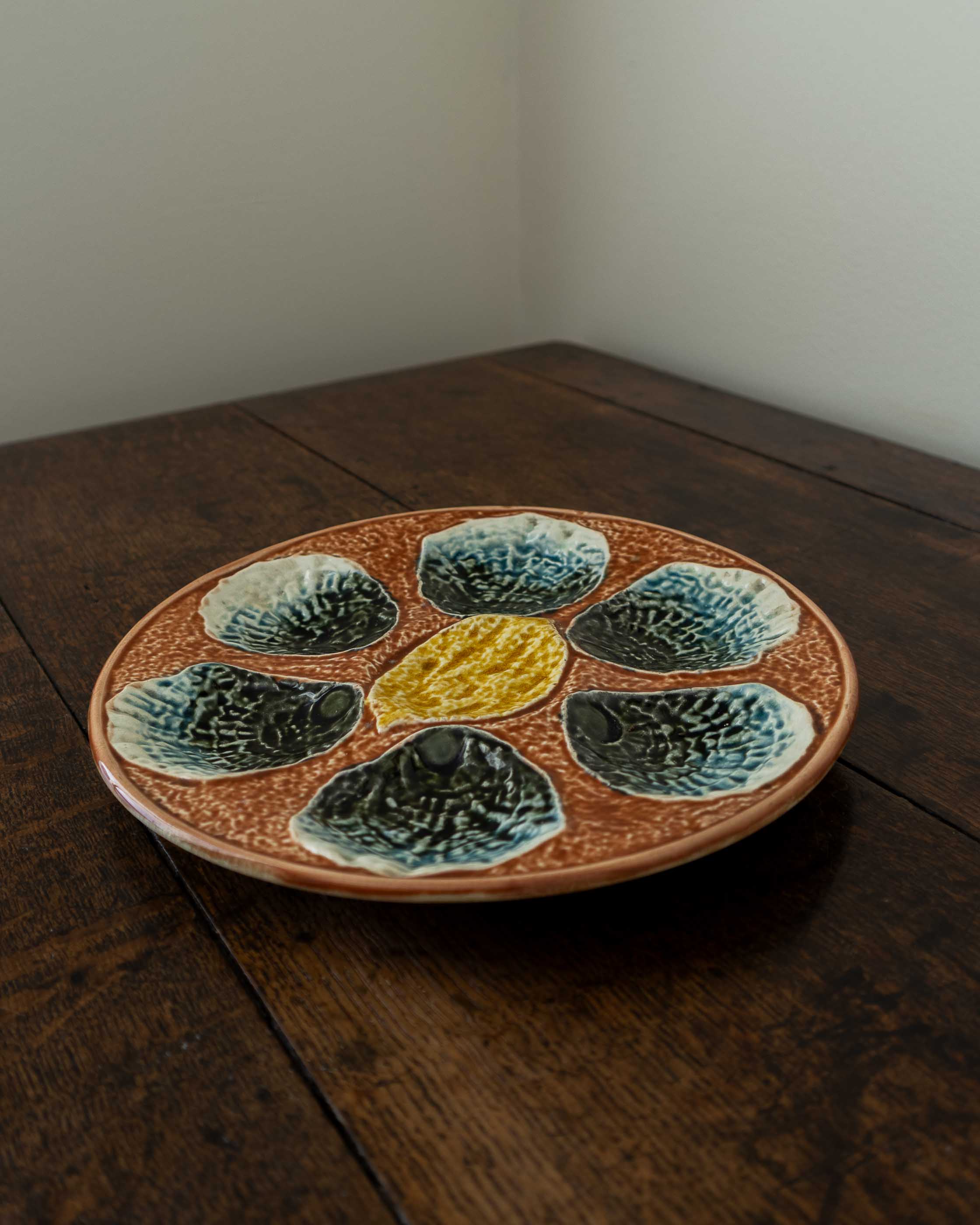 Ceramic majolica oyster plate with shell design on a wooden surface