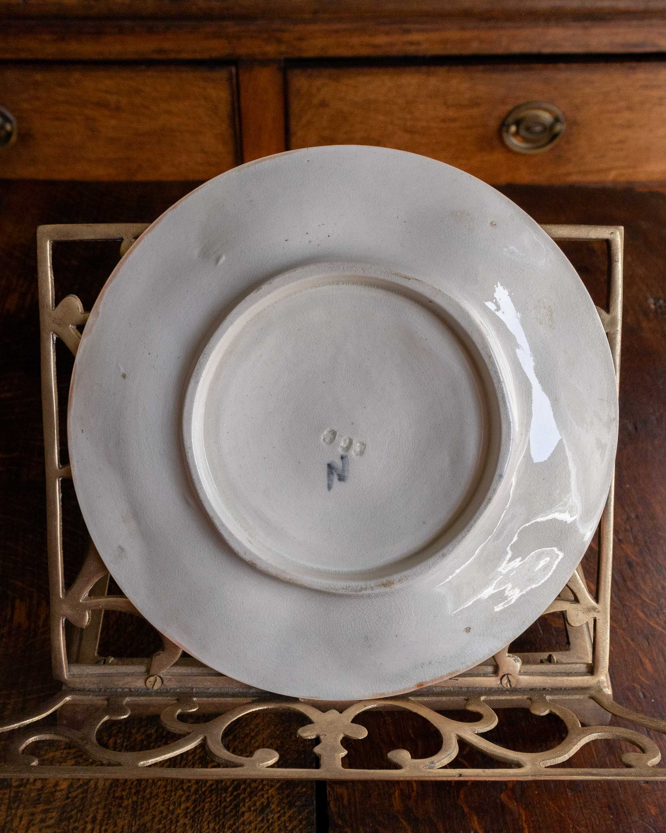 White ceramic plate on a decorative metal stand with wooden cabinet in the background