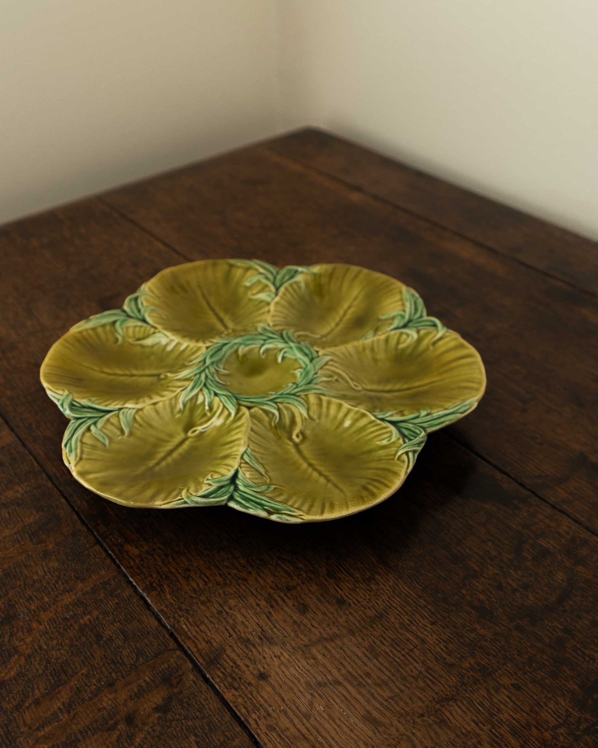 Decorative green oyster plate with green shell patterns on a wooden surface 