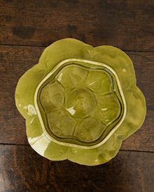 Decorative green oyster plate with green shell patterns on a wooden surface 