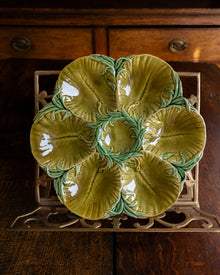 Decorative green oyster plate with green shell patterns on a wooden surface 
