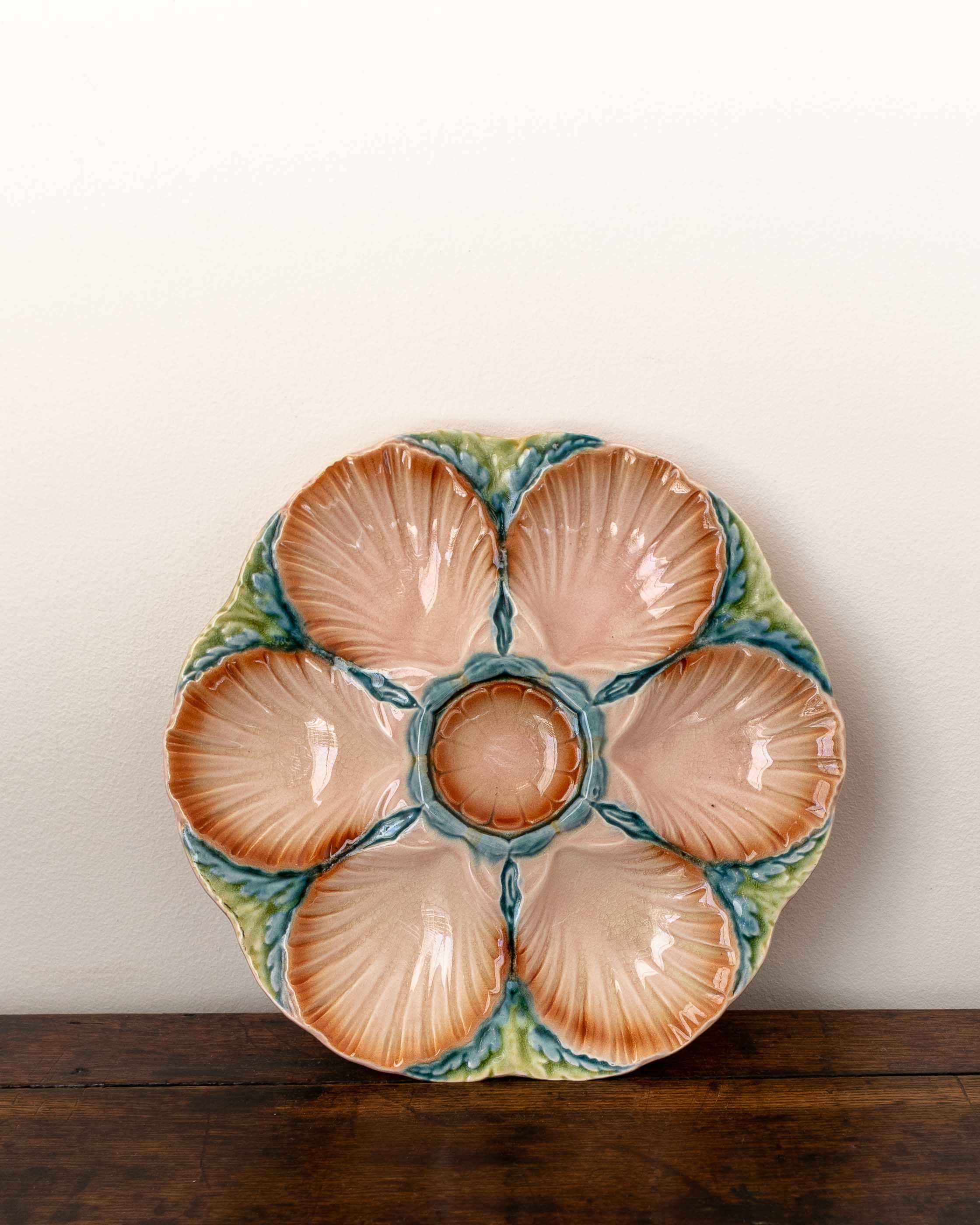 Ceramic oyster plate with shell design on a wooden surface and white background