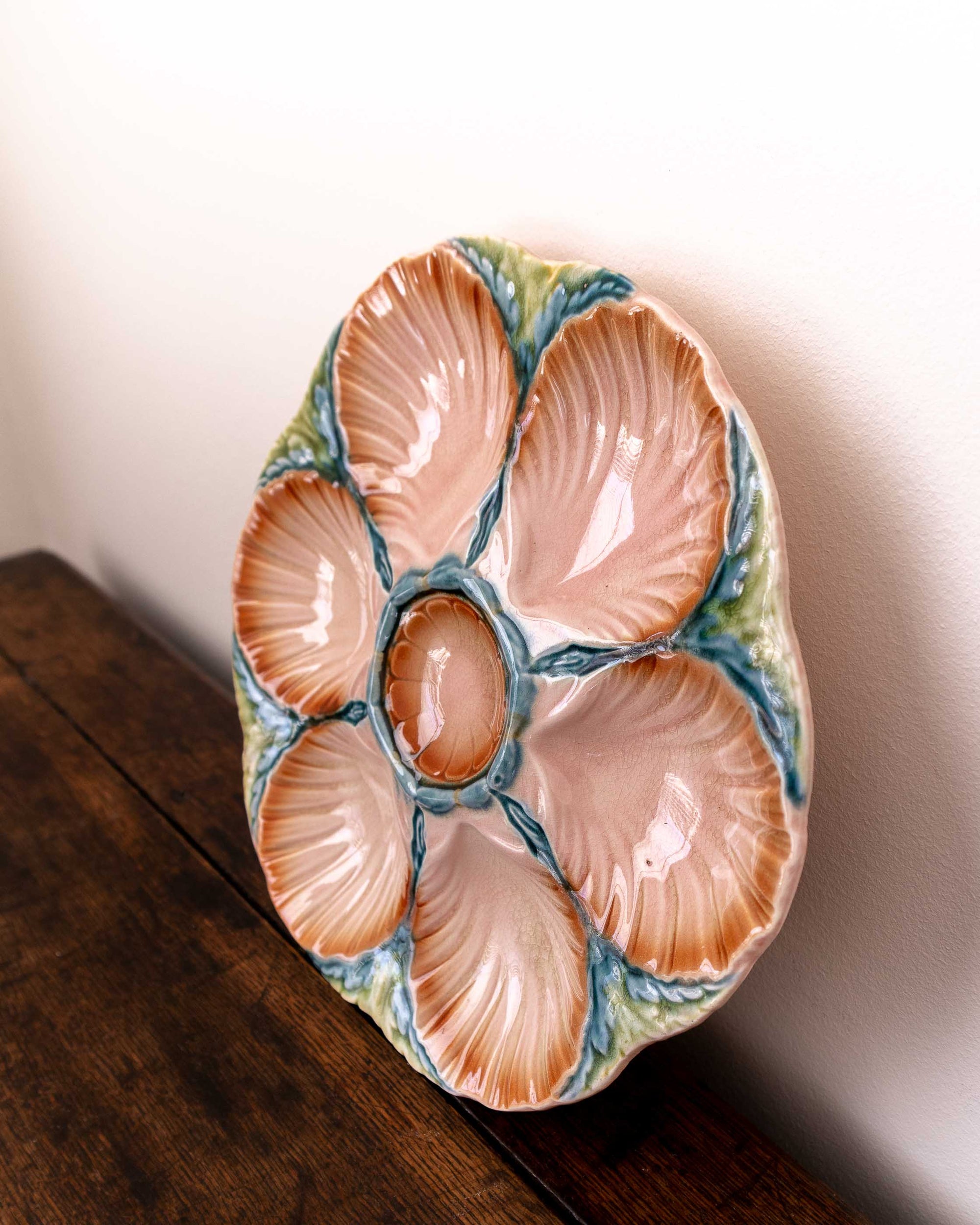 Ceramic oyster shell plate with scallop shells on a wooden surface
