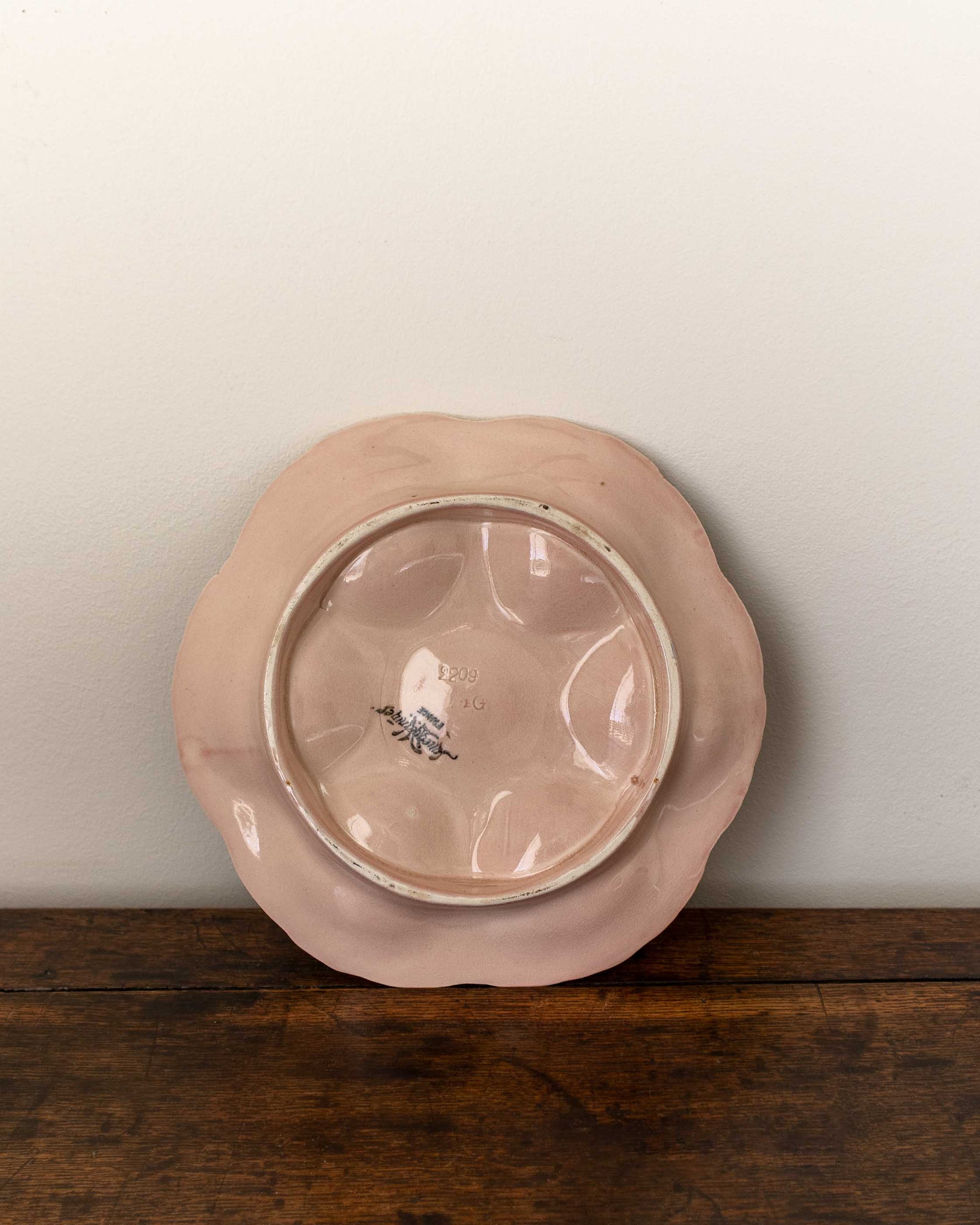 Pink ceramic plate with a decorative edge on a wooden surface
