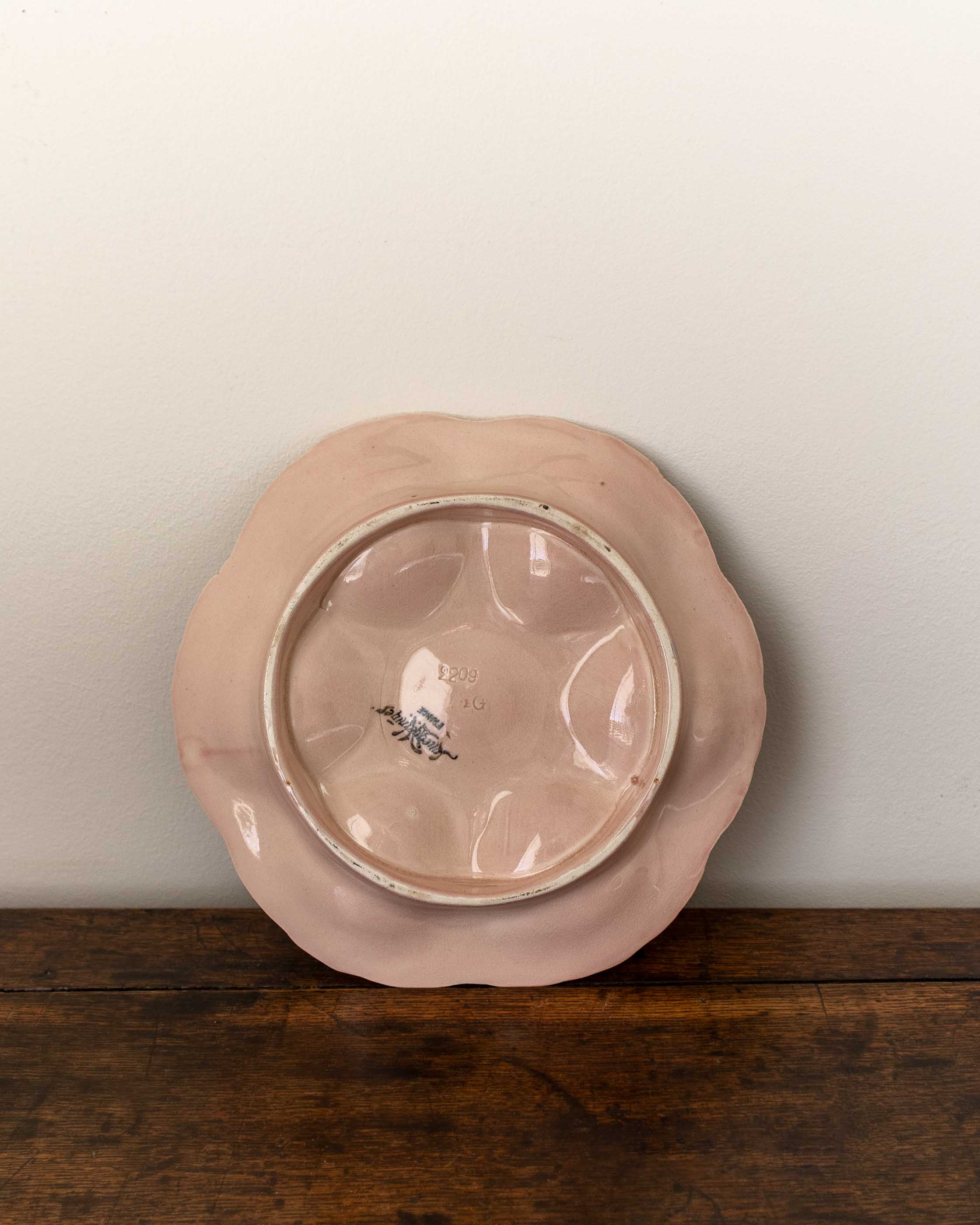 Pink ceramic plate with a decorative edge on a wooden surface