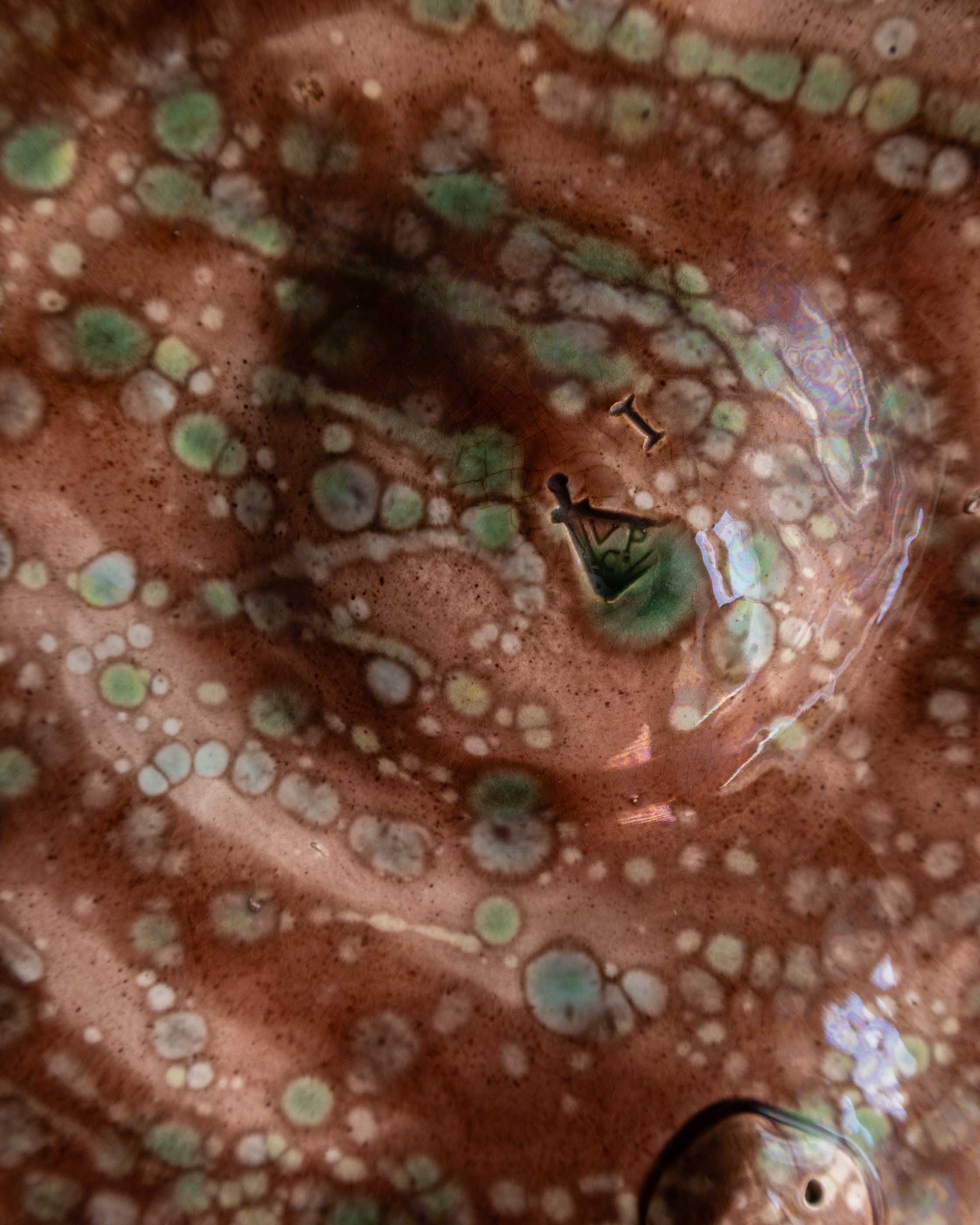 Close-up of a ceramic piece with a spotted surface and visible branding.