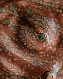Close-up of a ceramic piece with a spotted surface and visible branding.
