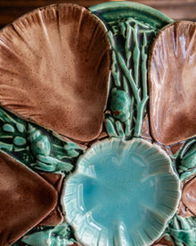 Close-up of a ceramic oyster plate with shells and seaweed designs