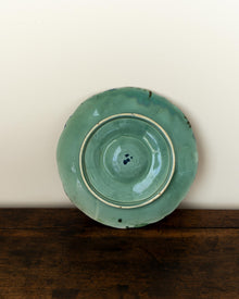 Green ceramic plate on a wooden surface with a white background
