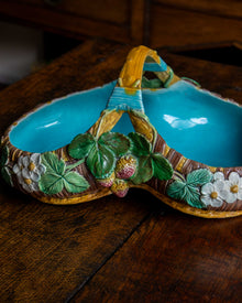 Decorative majolica ceramic strawberry dish with floral patterns on a wooden surface