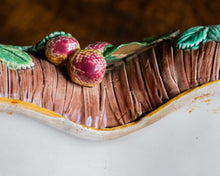 Close-up of a ceramic dish resembling with fruit and leaves on top.