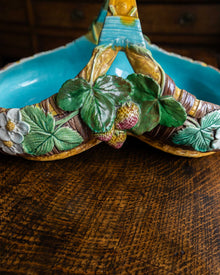 Decorative ceramic cornucopia with leaves and berries on a wooden surface