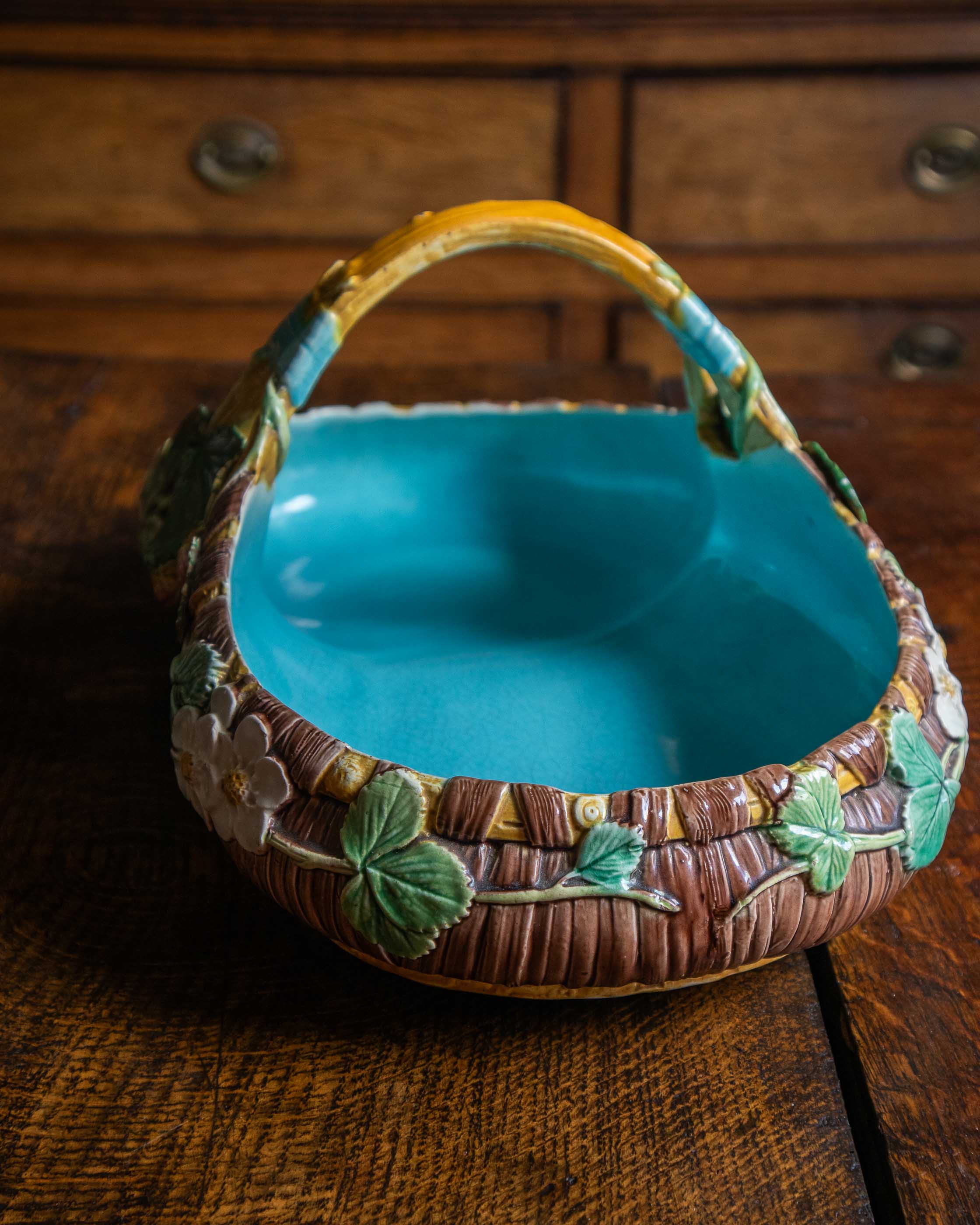 Decorative ceramic basket with a blue interior on a wooden surface
