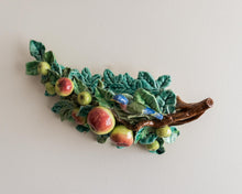 Decorative ceramic leaf with apples on a plain background