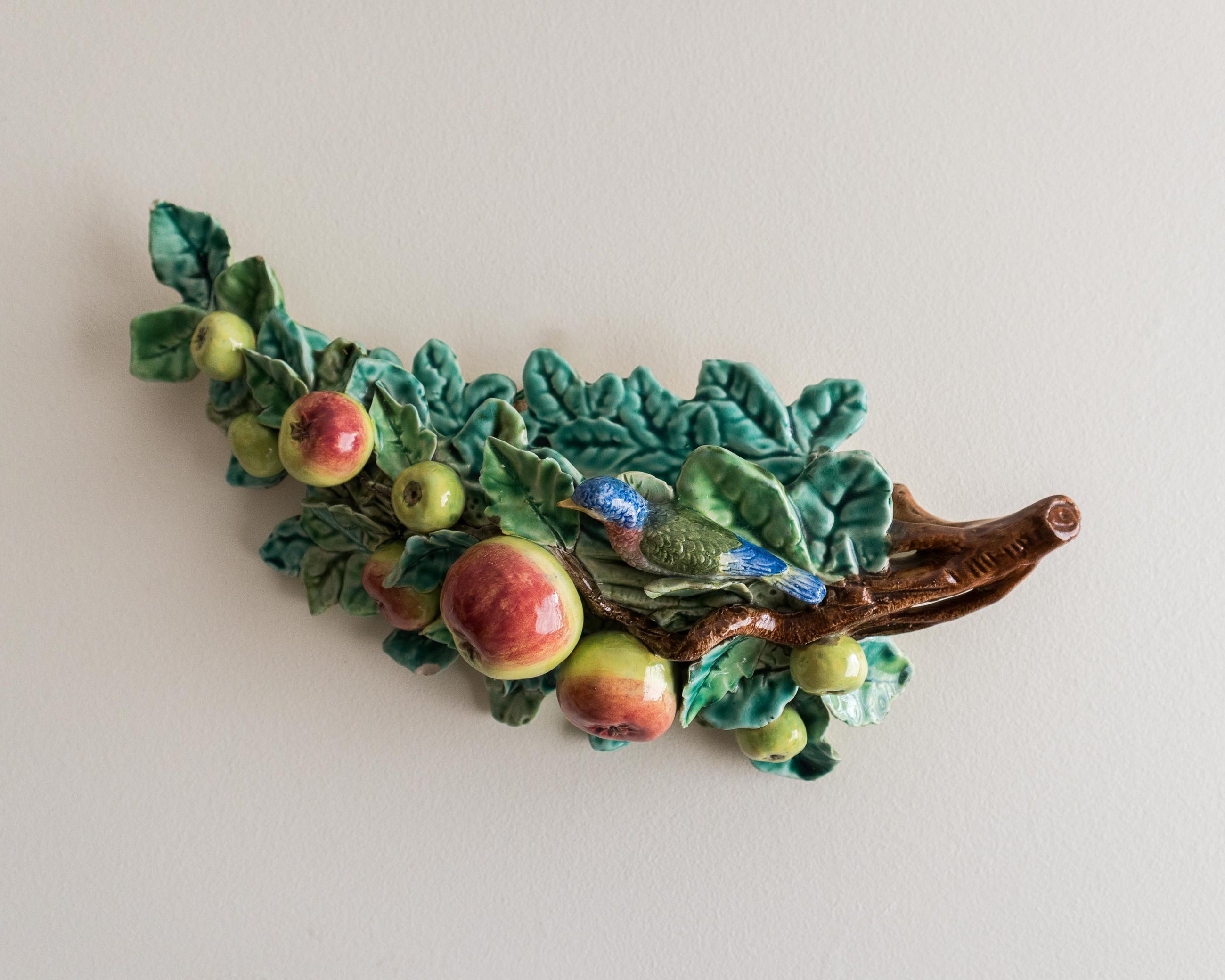 Decorative ceramic leaf with apples on a plain background