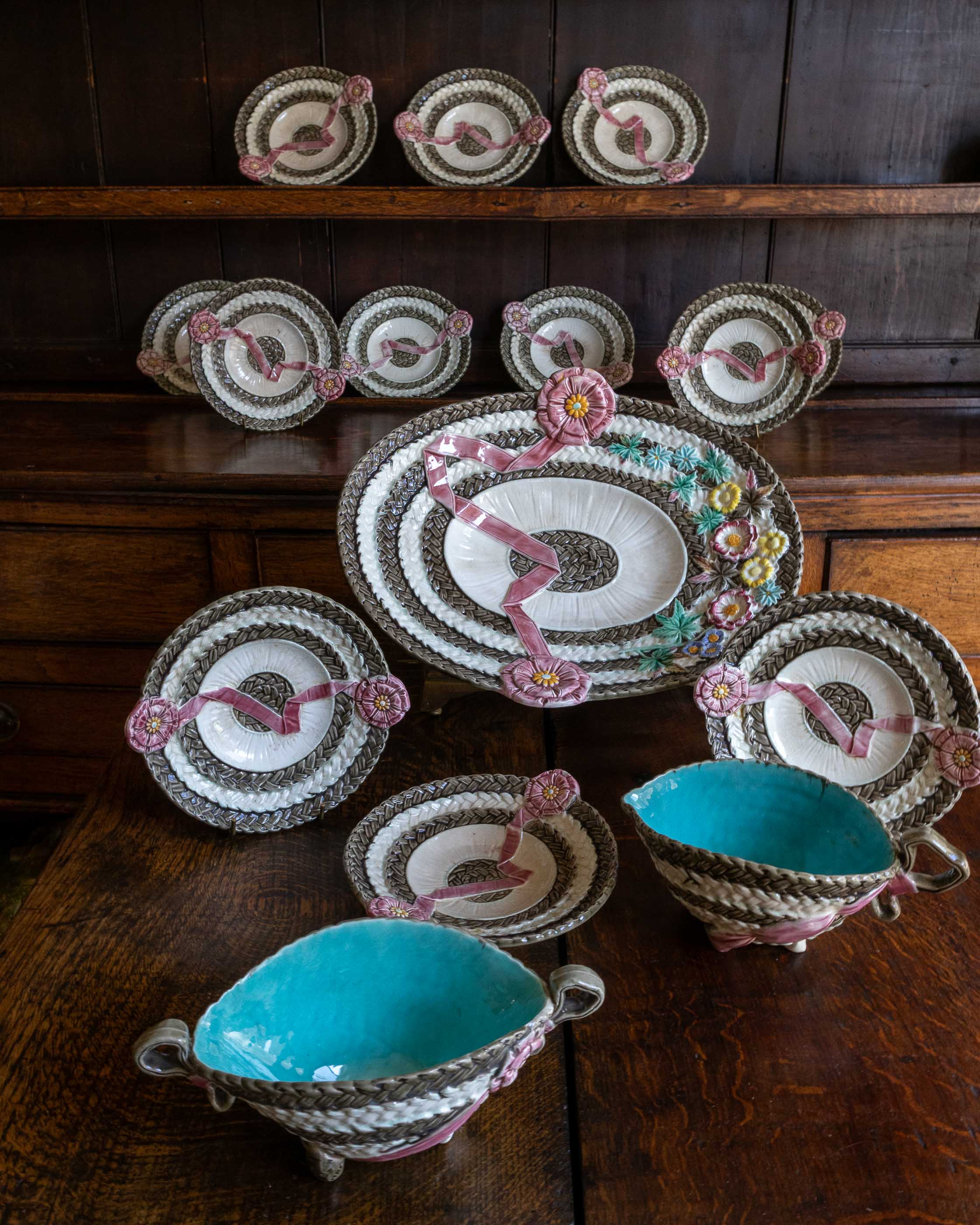 Decorative Wedgwood majolica ceramic plates and bowls with floral designs on a wooden surface.
