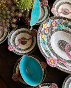 Decorative plates with floral embroidery and blue centers on a wooden surface.