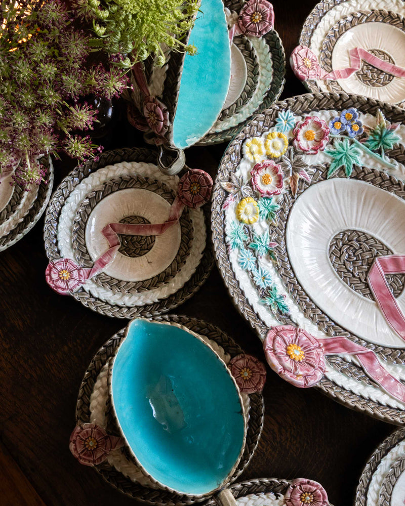 Decorative wedgwood majolica plates with floral embroidery and blue centers on a wooden surface.