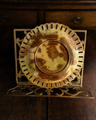 Decorative ceramic plate on a gold stand on a wooden surface