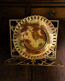 Decorative ceramic plate on a gold stand on a wooden surface