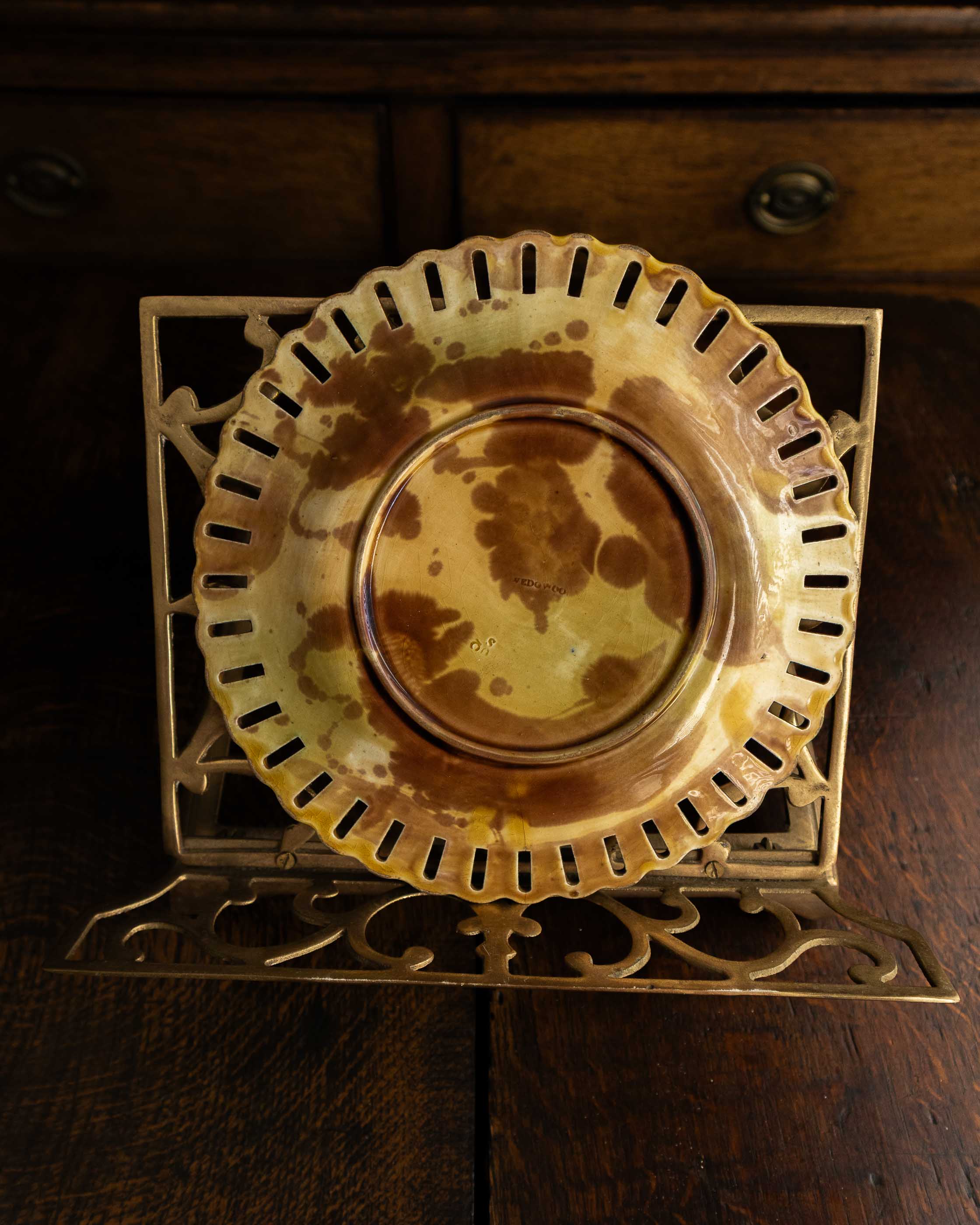 Decorative ceramic plate on a gold stand on a wooden surface