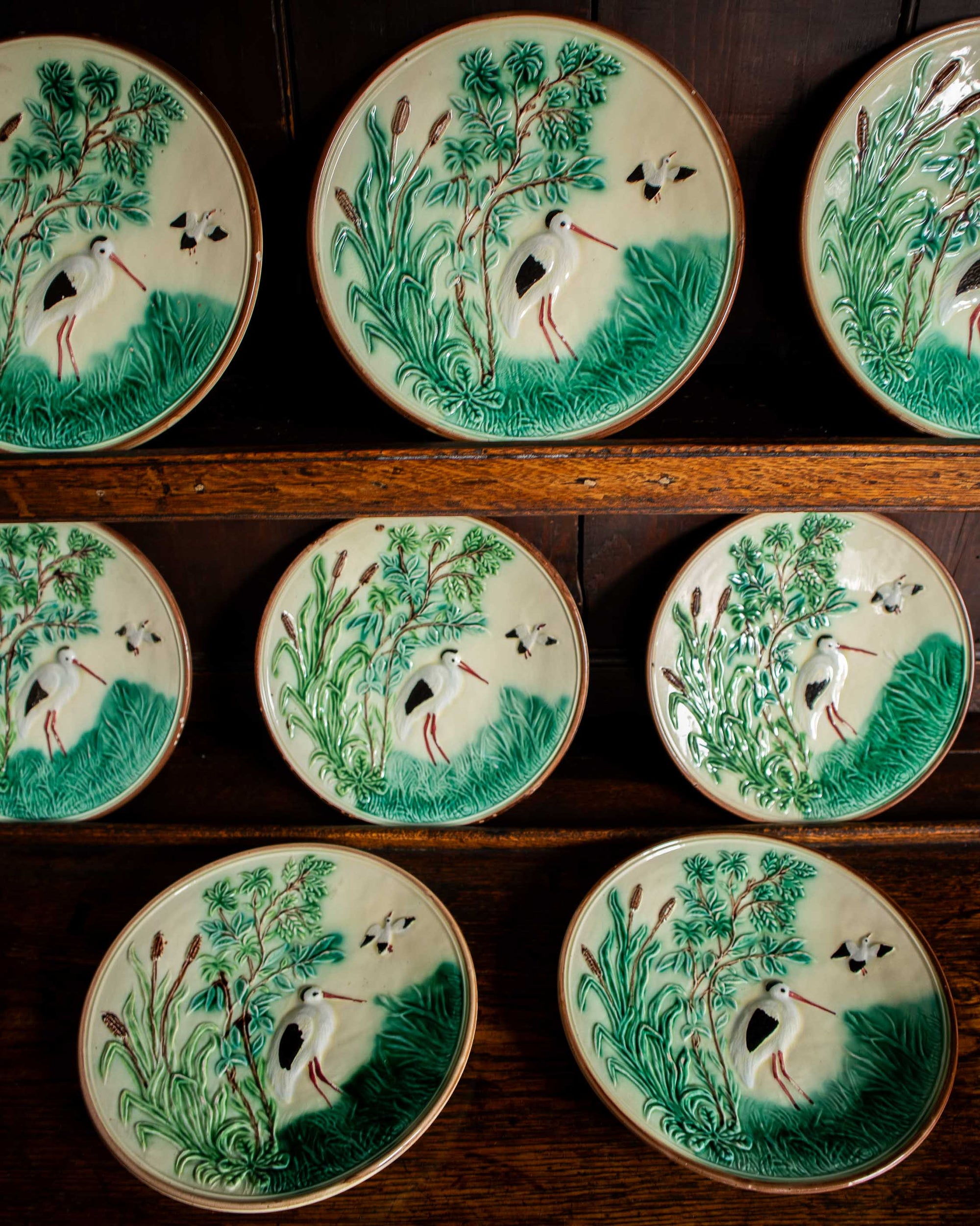 Set of ceramic plates with nature-themed designs on a wooden shelf.