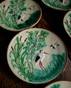 Decorative ceramic plates with bird and nature scenes on a wooden surface
