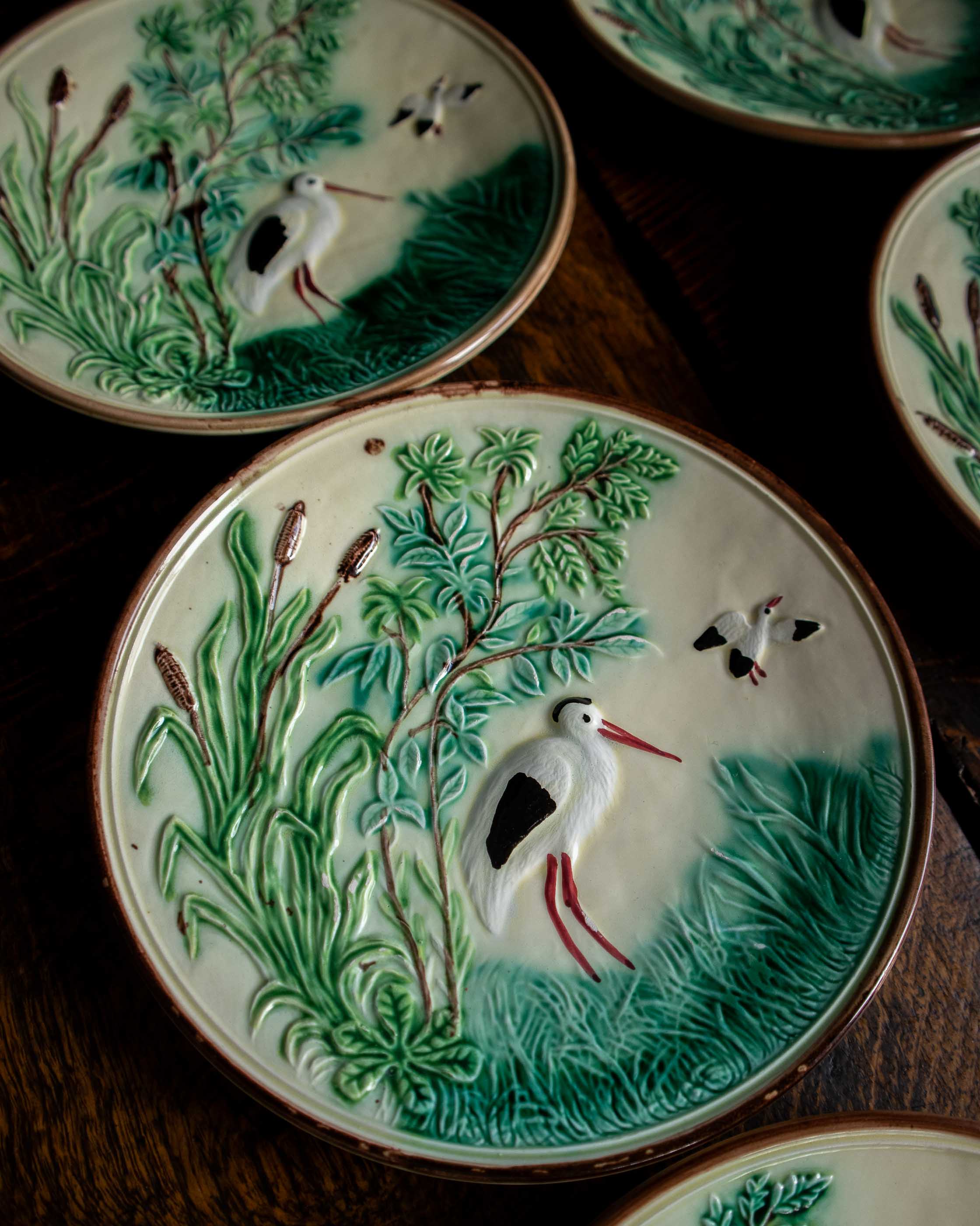 Decorative ceramic plates with bird and nature scenes on a wooden surface