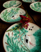 Decorative ceramic plates with nature-themed designs on a wooden surface.