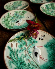 Decorative ceramic plates with nature-themed designs on a wooden surface.
