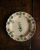 Decorative ceramic plate with green floral patterns on a wooden surface