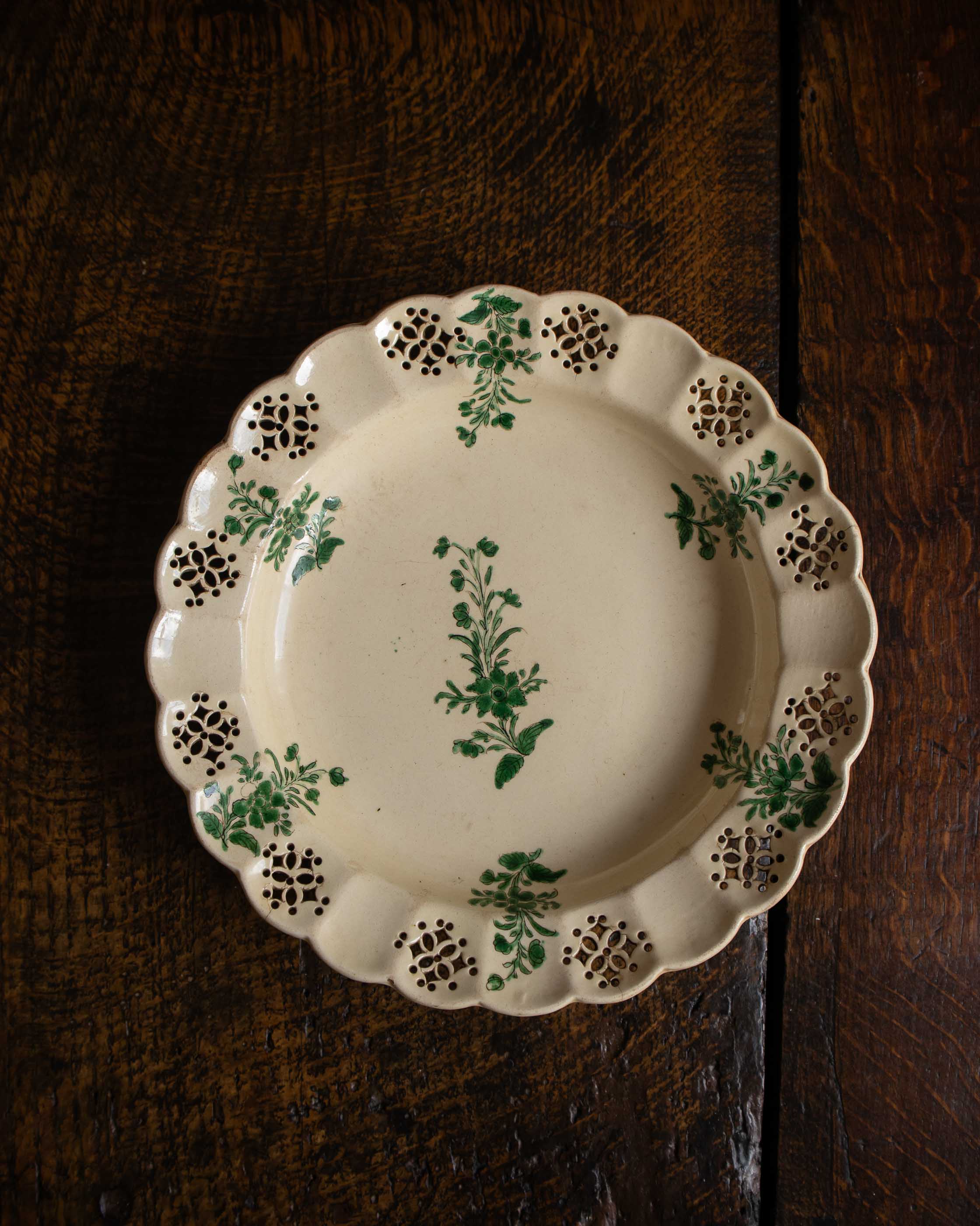 Decorative ceramic plate with green floral patterns on a wooden surface