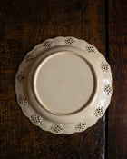 White ceramic plate with decorative edge on a wooden surface