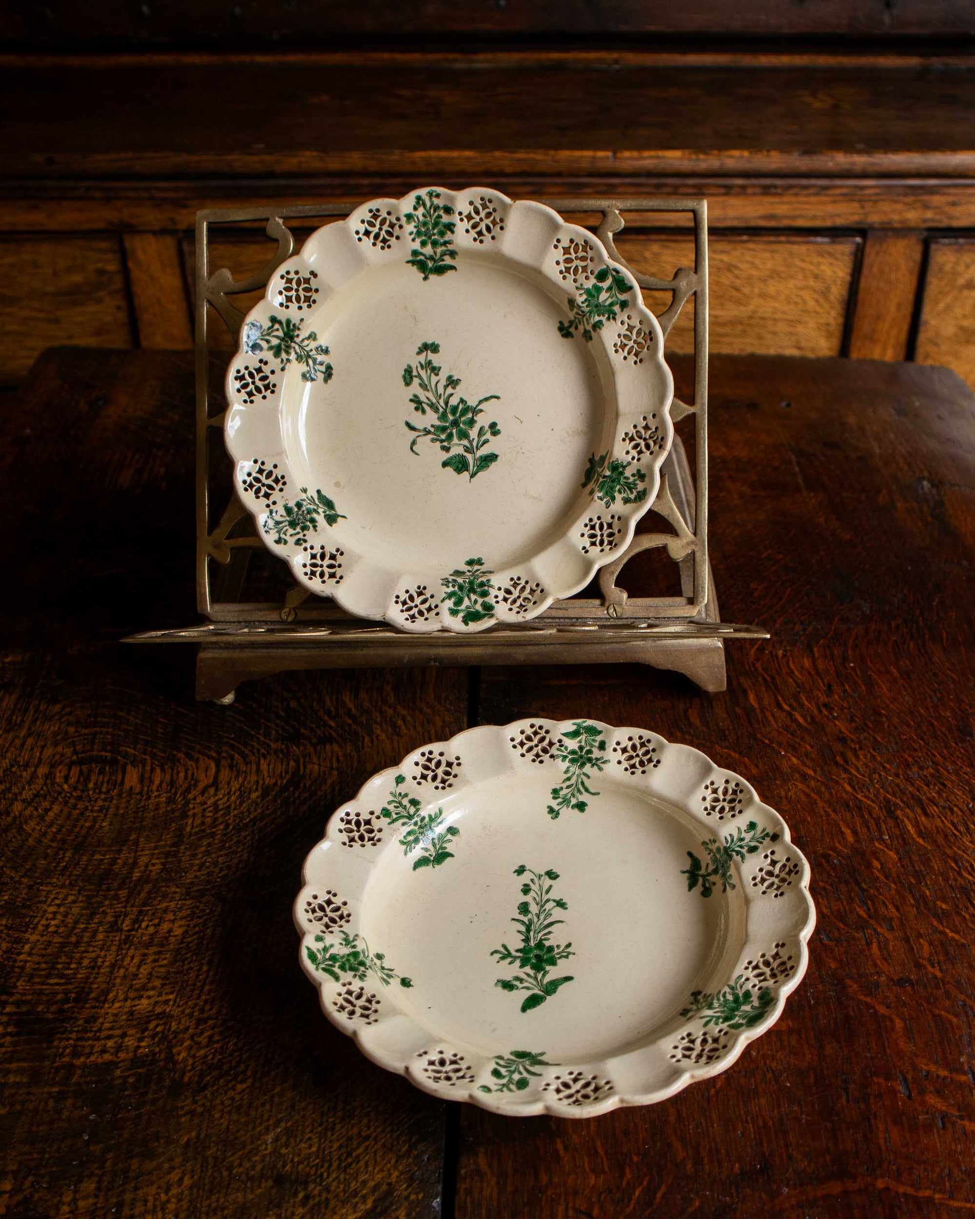 Two decorative plates with green floral patterns on a wooden surface.