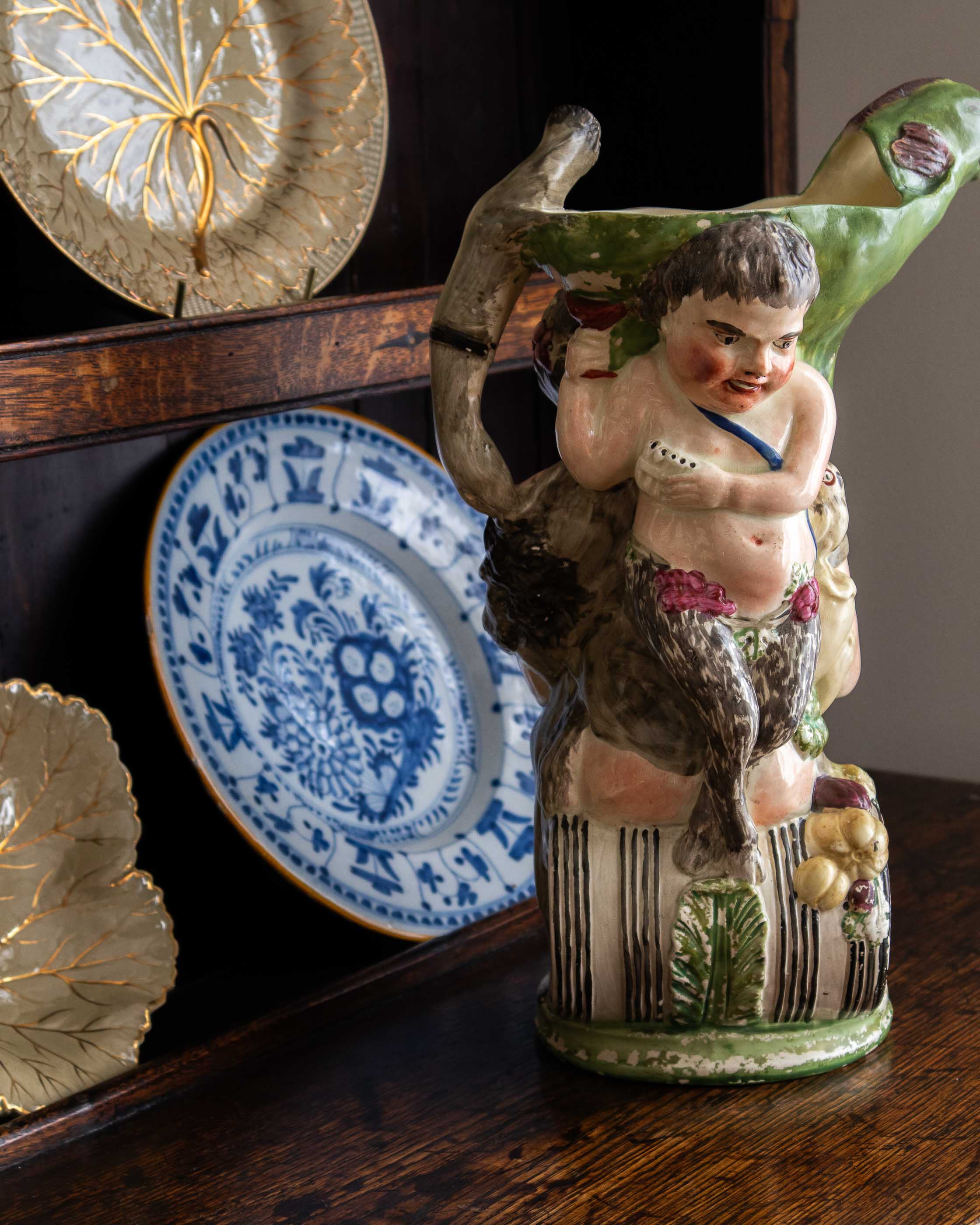 Decorative ceramic figure of a bacchus with a wine glass on a wooden surface.