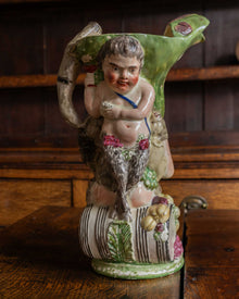 Decorative ceramic figure of a bacchus with floral elements on a wooden surface