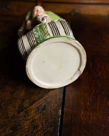 Ceramic jug with green and white design on a wooden surface