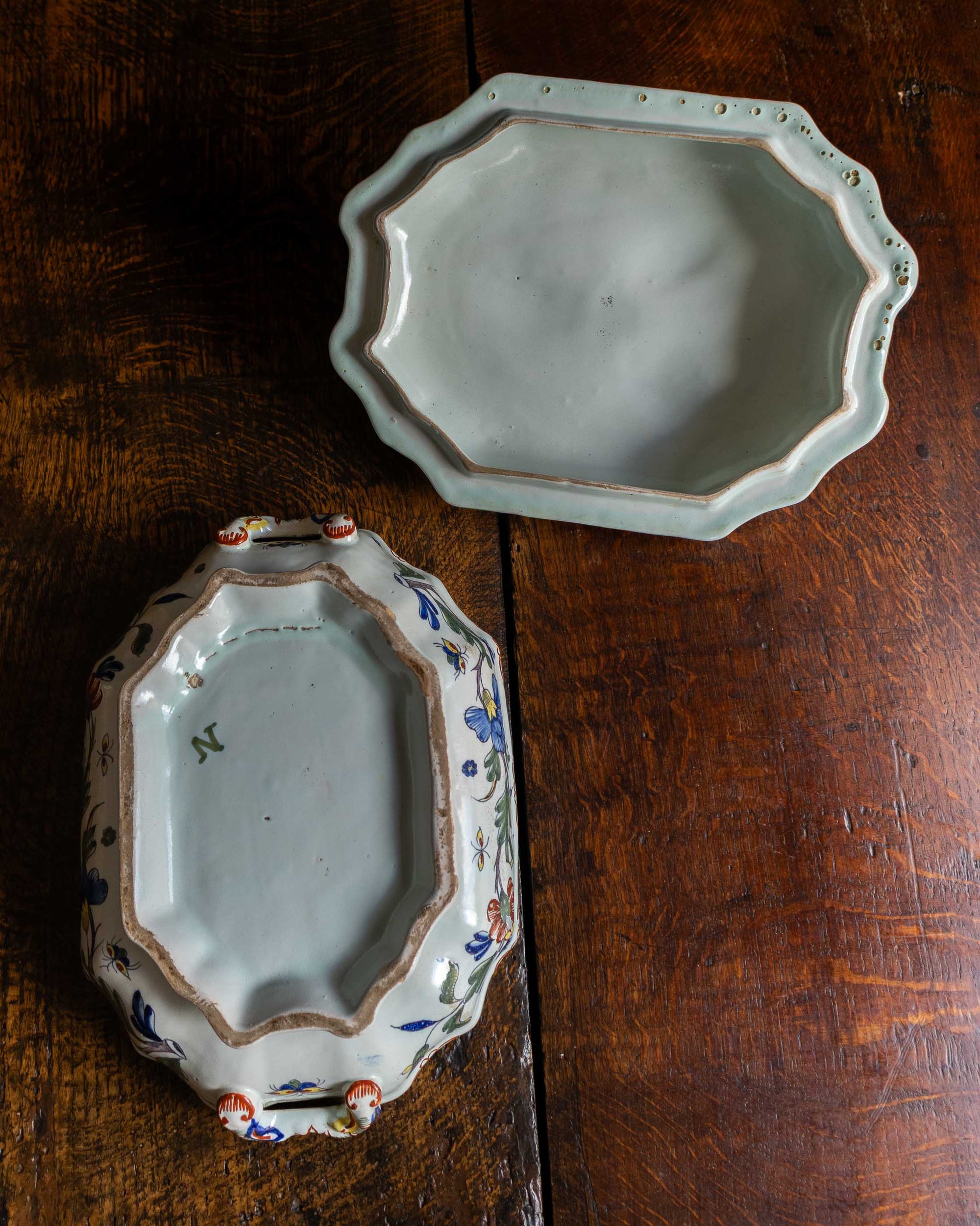 Two ceramic tureen and lid on a wooden surface, one with decorative patterns.
