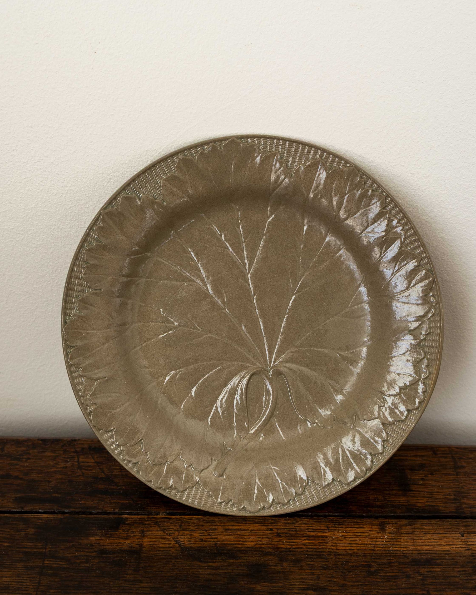 Decorative ceramic plate with leaf pattern on a wooden surface
