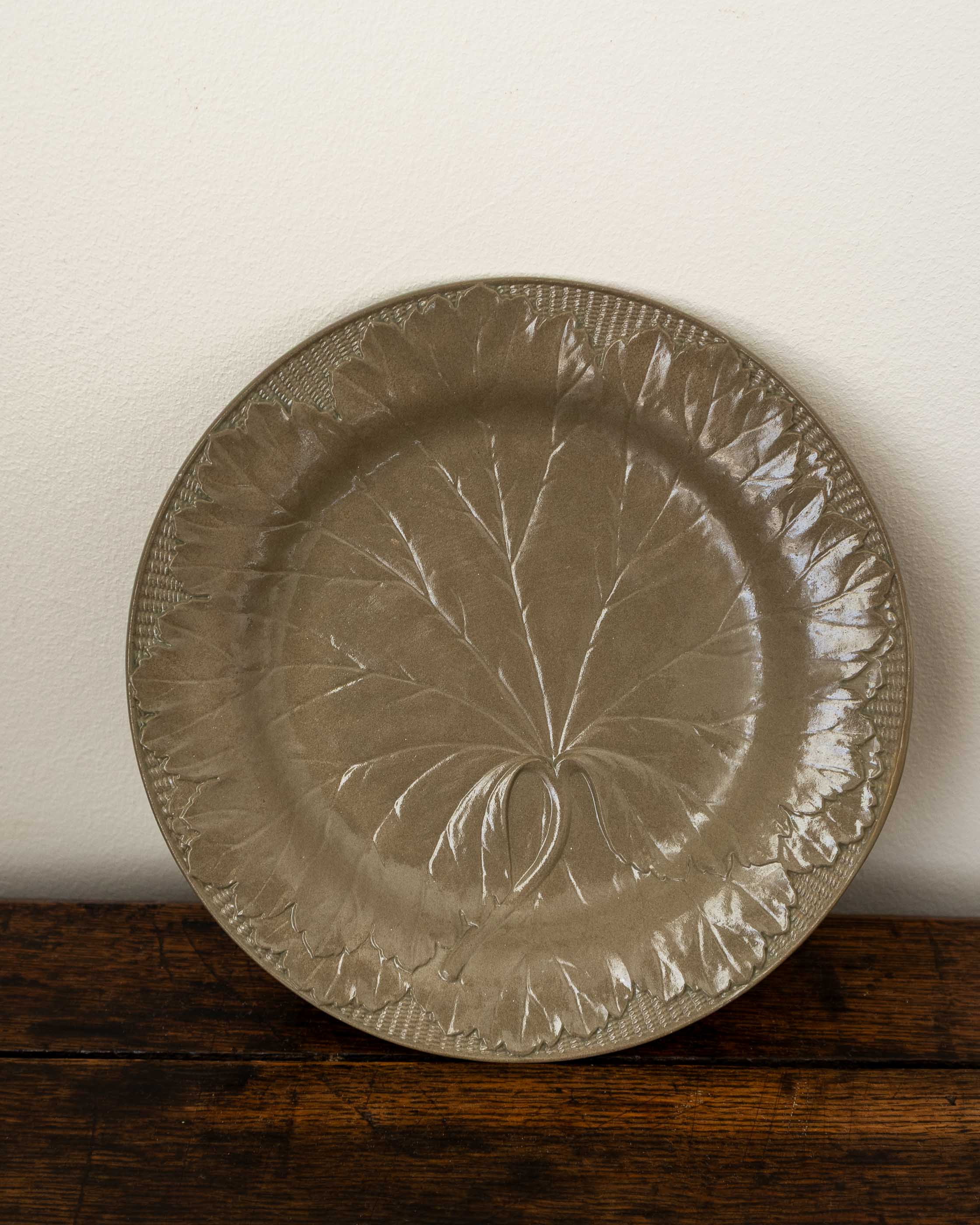 Decorative ceramic plate with leaf pattern on a wooden surface